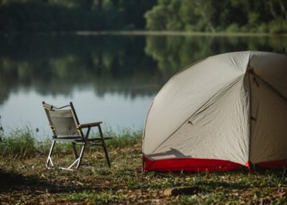 camping setup with a tent and folding chair beside a lake, illustrating the kind of outdoor scene where portable solar blankets are useful