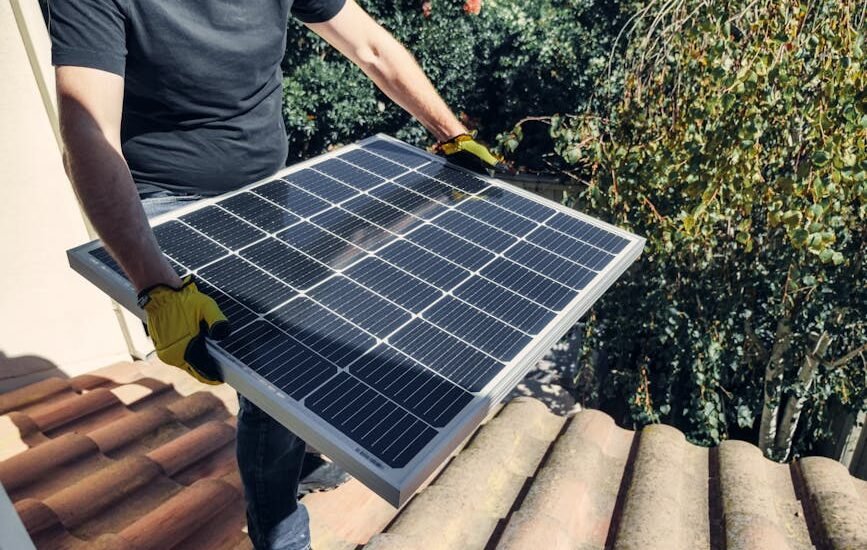 Person in gloves installing a solar panel on a tiled roof, illustrating steps in choosing a solar generator kit for home backup power.