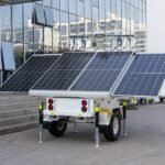 A mobile solar generator trailer with large solar panels is parked outside a modern building, illustrating off-grid power options for the gas vs propane generat