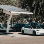 solar charge controller use shown by a solar-powered EV charging station with electric cars parked underneath in a lot