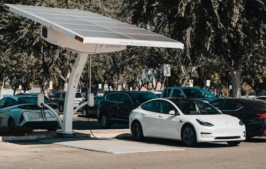 solar charge controller use shown by a solar-powered EV charging station with electric cars parked underneath in a lot