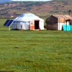 Portable solar panel set up next to a yurt on open grassland, illustrating off-grid camping power options.