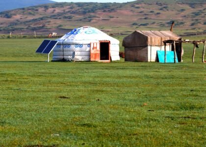 Portable solar panel set up next to a yurt on open grassland, illustrating off-grid camping power options.