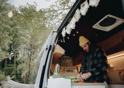 Person preparing food inside a camper van kitchen, illustrating van life and the use of 12V refrigerators for off-grid living.