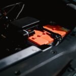 Lithium battery with orange casing installed in an RV engine compartment, illustrating RV lithium battery setup for the best battery review article.