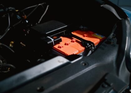 Lithium battery with orange casing installed in an RV engine compartment, illustrating RV lithium battery setup for the best battery review article.