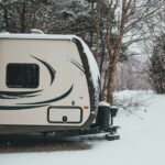 RV parked in a snowy forest, illustrating the need for reliable RV power converters in cold weather conditions.