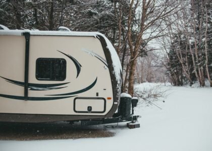 RV parked in a snowy forest, illustrating the need for reliable RV power converters in cold weather conditions.