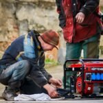 Two people working on a red portable inverter generator outdoors, illustrating hands-on maintenance for reliable off-grid power solutions.