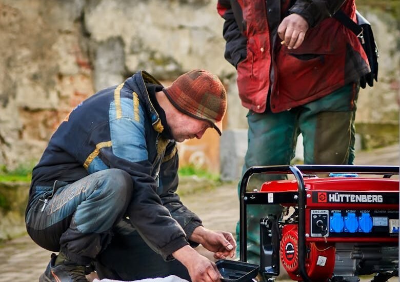 Two people working on a red portable inverter generator outdoors, illustrating hands-on maintenance for reliable off-grid power solutions.