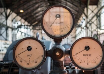 Three vintage analog meters labeled volt, ampere, and kilowatt illustrate the difference between amp hours and watt hours.