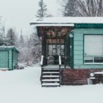 A snowy scene featuring a green cabin and storage sheds, relevant to dual fuel generators.