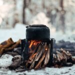 A campfire setup with a kettle on top, illustrating outdoor heating methods relevant to battery-operated heaters.