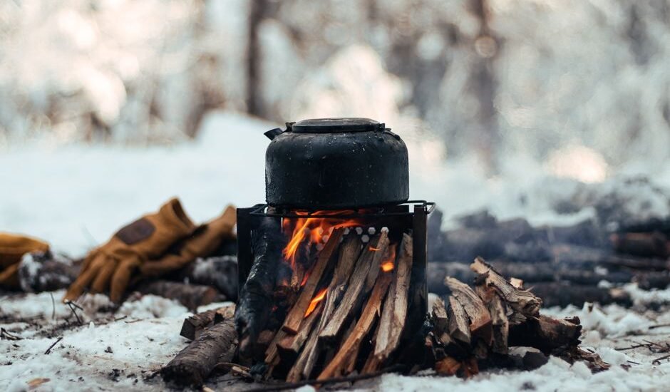 A campfire setup with a kettle on top, illustrating outdoor heating methods relevant to battery-operated heaters.