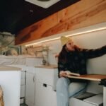 A man reading in an RV interior featuring 12V LED lights with a switch.