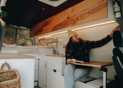 A man reading in an RV interior featuring 12V LED lights with a switch.