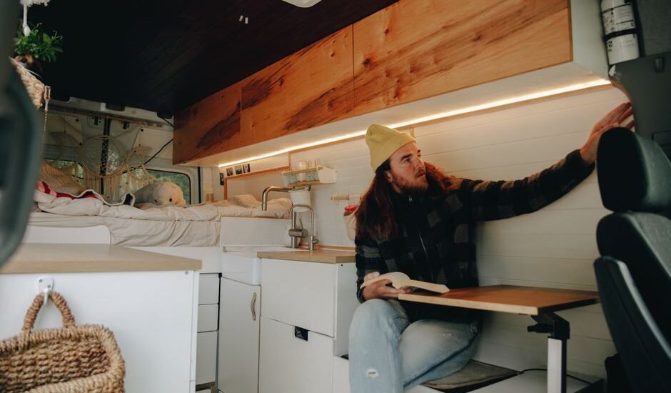 A man reading in an RV interior featuring 12V LED lights with a switch.