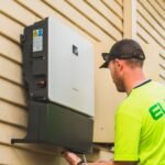 A technician installs an all-in-one inverter charger on a wall, relevant to inverter charger buying guide.