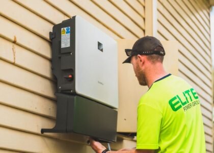 A technician installs an all-in-one inverter charger on a wall, relevant to inverter charger buying guide.