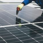 A worker installs solar panels, relevant to high-capacity lithium-ion batteries.
