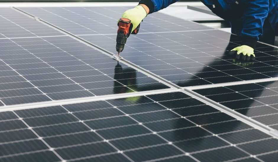 A worker installs solar panels, relevant to high-capacity lithium-ion batteries.