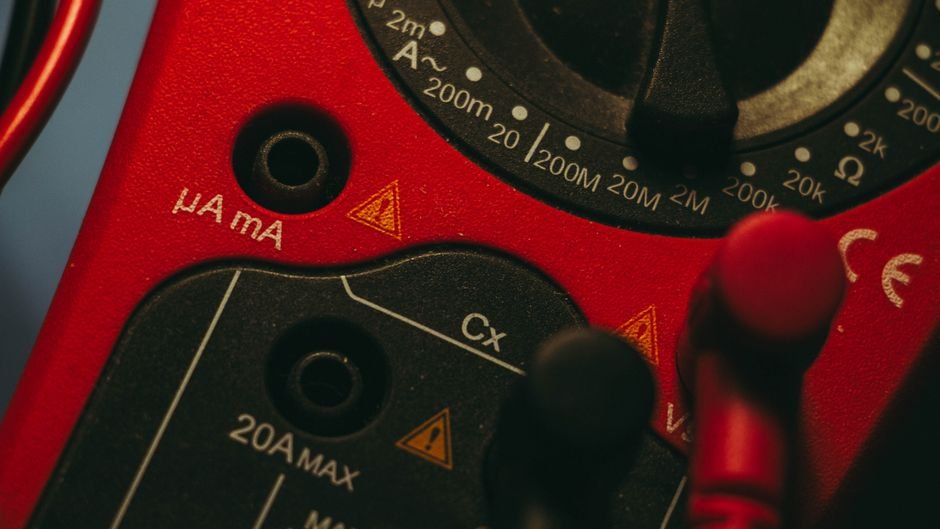 A close-up of a multimeter showing settings for measuring appliance power consumption.