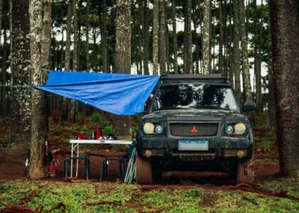 A vehicle with a tarp setup in a forest, illustrating off-grid living options like power stations and batteries.