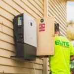 A technician installs a solar inverter on a wall, relevant to solar inverter idle consumption.