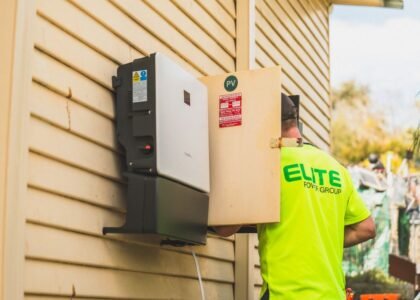 A technician installs a solar inverter on a wall, relevant to solar inverter idle consumption.