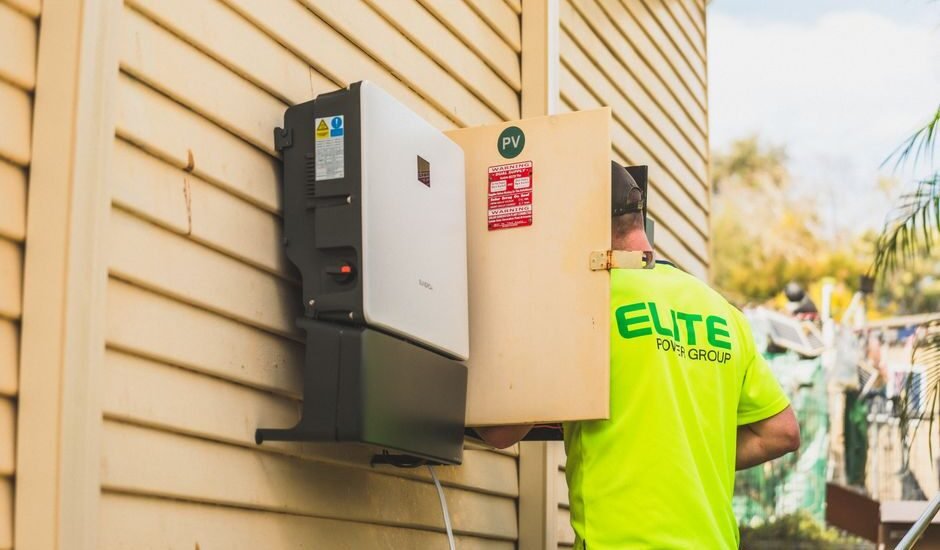 A technician installs a solar inverter on a wall, relevant to solar inverter idle consumption.