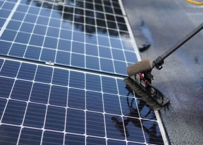 A person using a brush to clean solar panels, illustrating effective cleaning techniques.