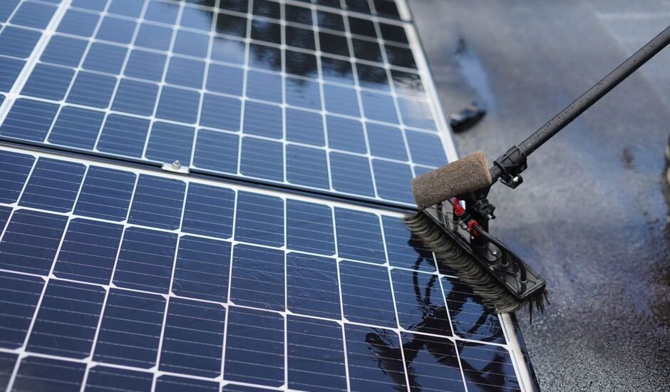 A person using a brush to clean solar panels, illustrating effective cleaning techniques.