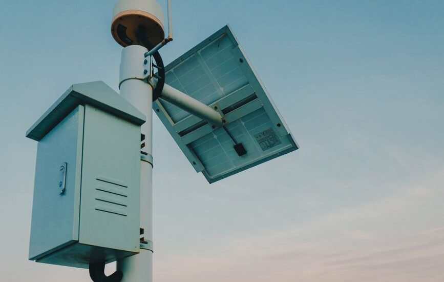 A solar panel mounted on a pole with a charge controller box, illustrating temperature compensation in solar systems.