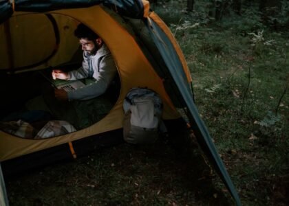 A person inside a tent using a laptop, illustrating the convenience of portable power stations for outdoor activities.