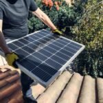 A person carrying a solar panel on a roof, relevant to lithium battery monitoring.