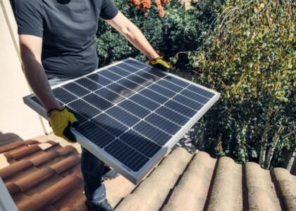 A person carrying a solar panel on a roof, relevant to lithium battery monitoring.