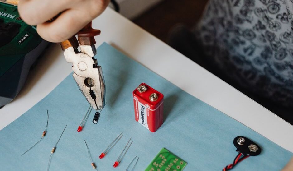A person using pliers to work on battery components, illustrating how to balance battery cells.