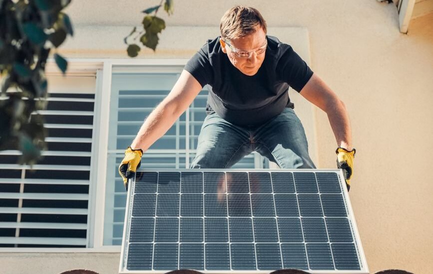 A person adjusting the angle of a solar panel on a roof, relevant to optimizing solar panel angle.