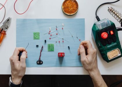 Hands working on electronic components for repairing a portable power station.