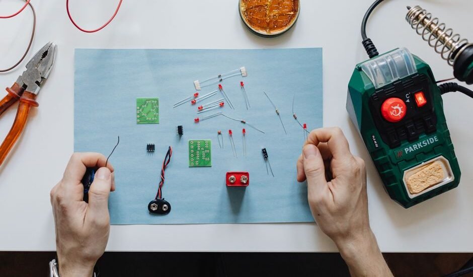 Hands working on electronic components for repairing a portable power station.