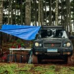 A camping scene featuring a vehicle with a tarp, illustrating outdoor power needs related to portable power stations and power banks.